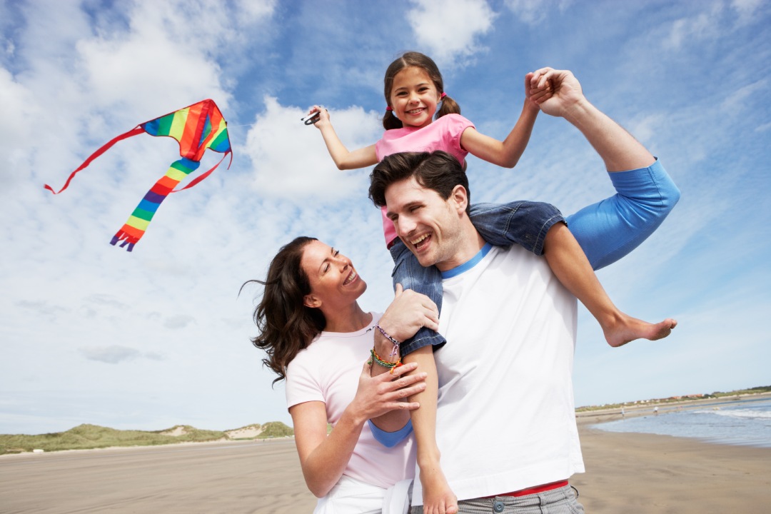 Family Having Fun Flying Kite On Beach Holiday